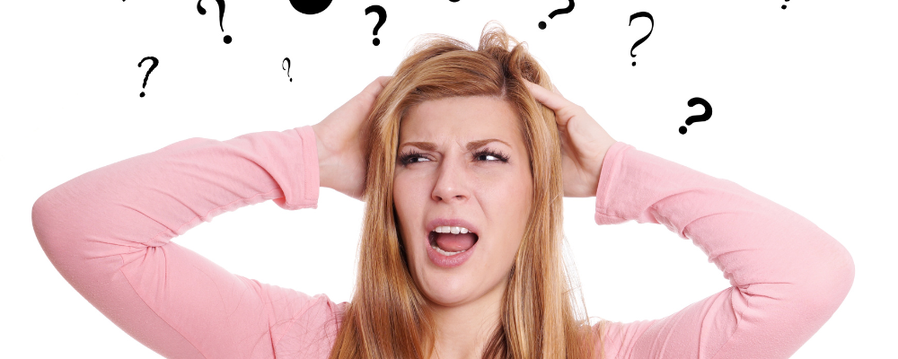 Woman holding her head with a confused look and question marks around her.